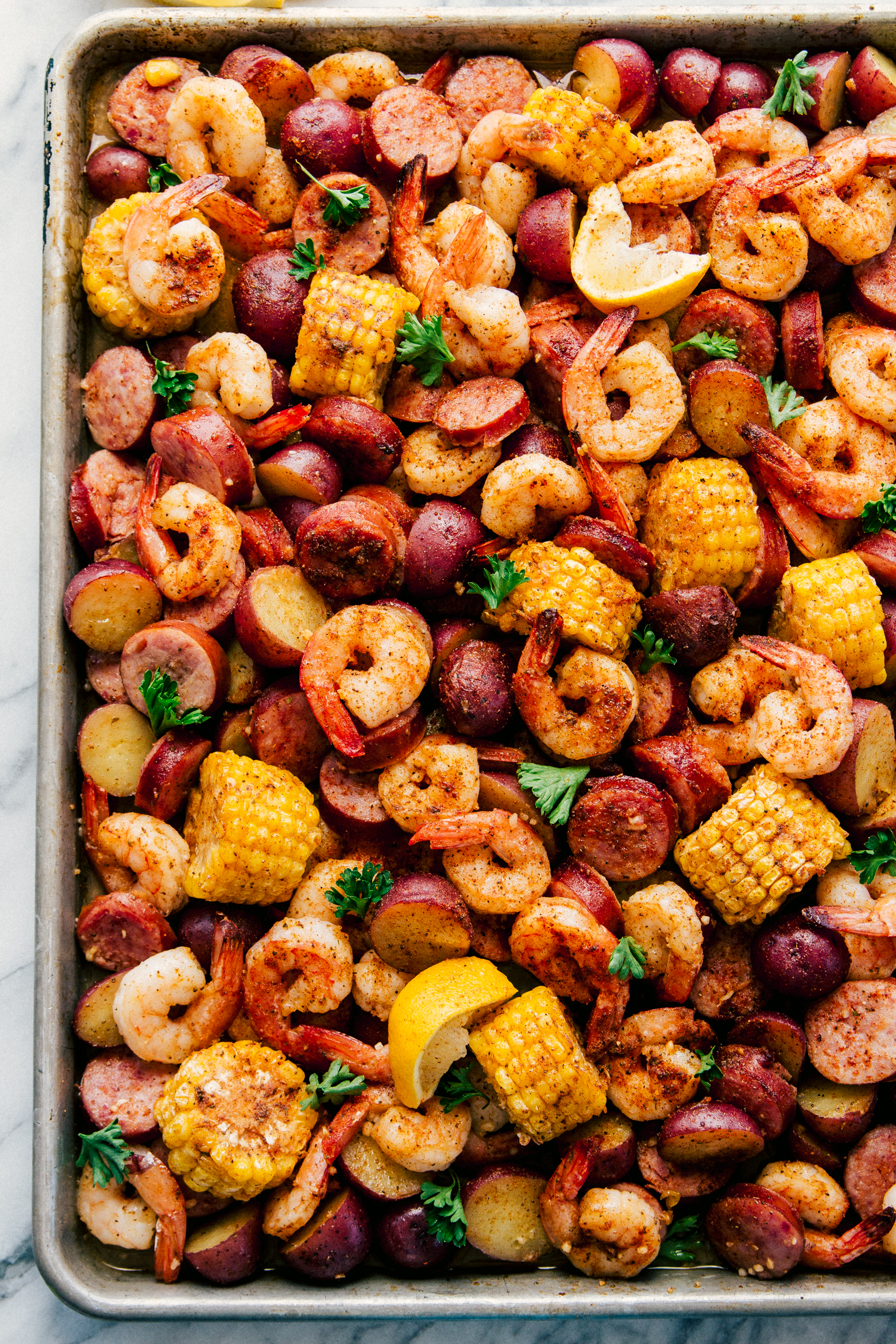 sheet pan garlic shrimp boil with sausage, corn, and red potatoes by The Food Cafe. 