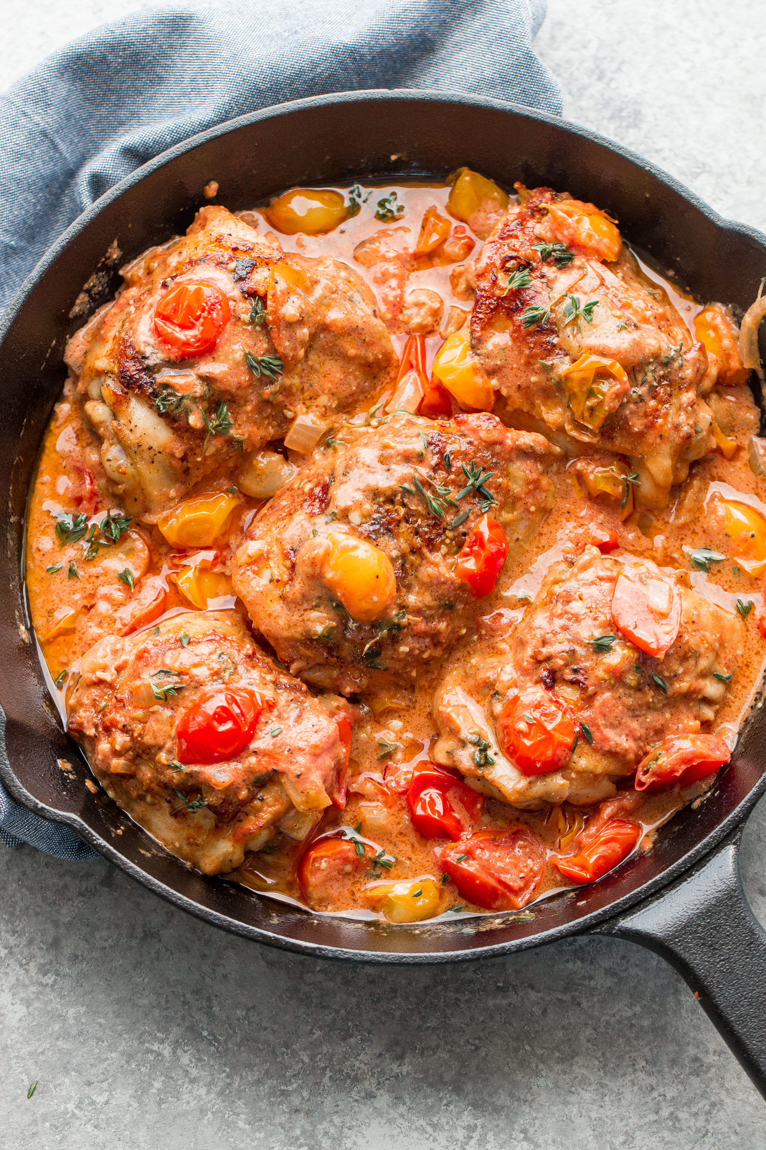 Garlic Chicken made in a skillet with a rich and creamy sauce and fresh tomatoes, by the food cafe. 