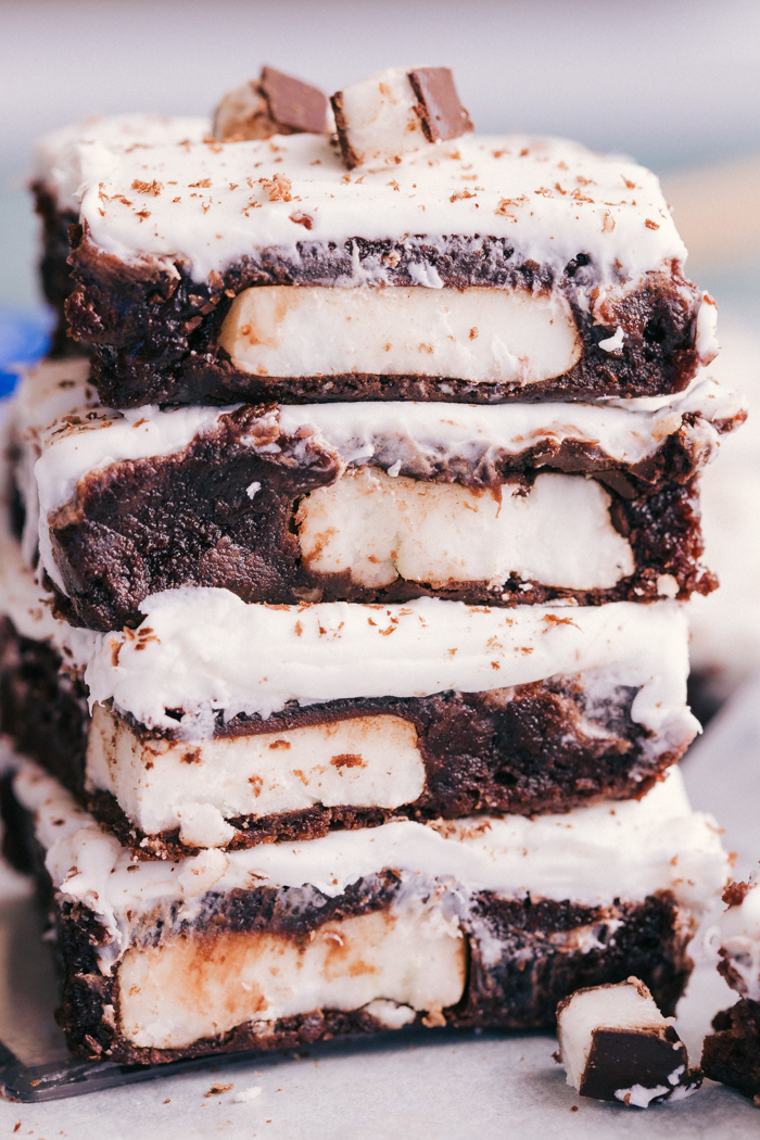 Peppermint patty brownies stacked on top of each other with shaved chocolate and chopped york peppermint patty's on top, by The Food Cafe. 