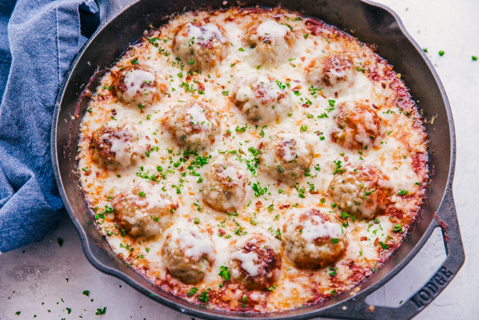 Parmesan Chicken meatballs in a skillet covered in melted cheese-perfect appetizer.