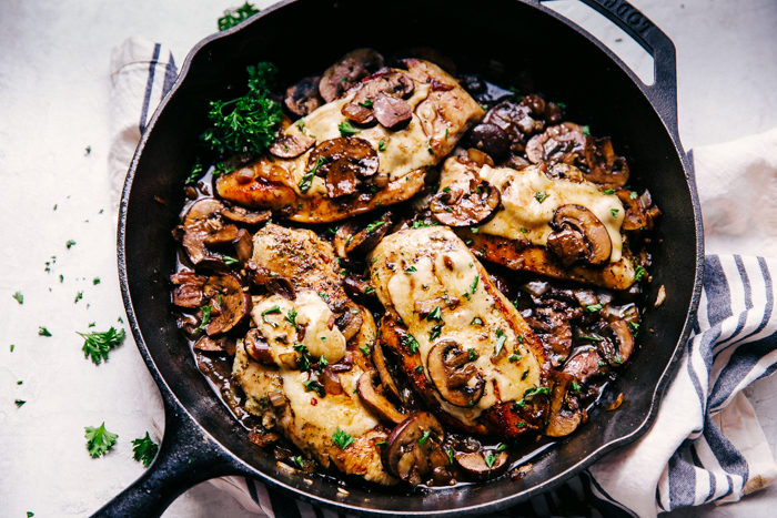 chicken and mushrooms baked in a black skillet topped with melted cheese by The Food Cafe. 