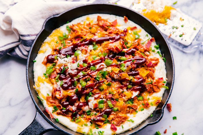 BBQ chicken and mashed potatoes in a skillet topped with cheese, bacon, and chives