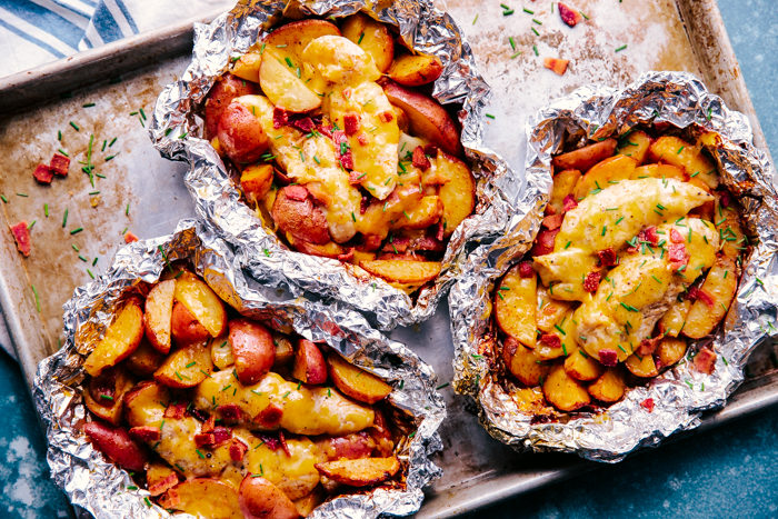 Chicken and Potatoes cooked in foil and served on a rimmed baking sheet for an easy weekend meal by The Food Cafe. 