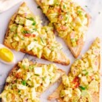 Egg salad on top of whole wheat bread with bacon and chives