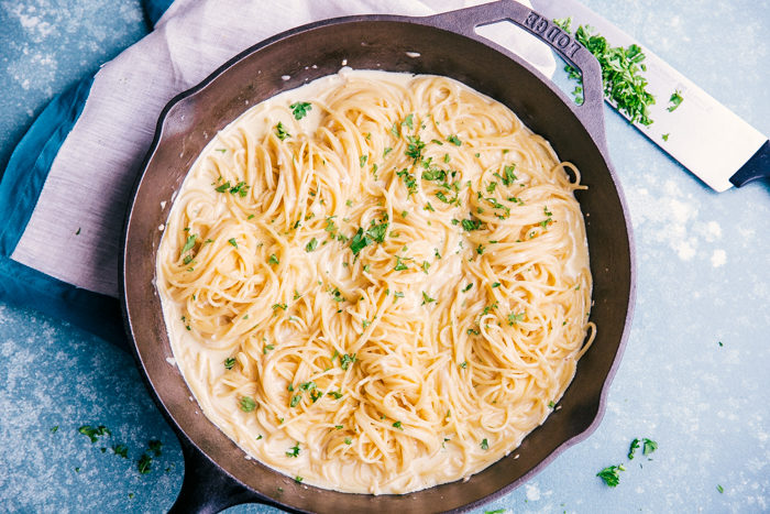 Garlic Butter Noodles in a large cast iron skillet topped with cream sauce. 
