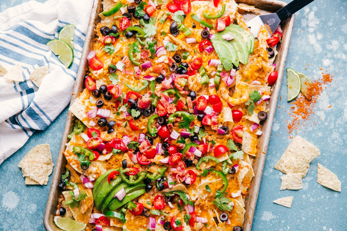 Sheet Pan chicken nachos topped with melted cheese and vegetables