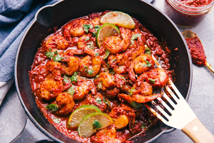cilantro lime shrimp in a skillet with adobe sauce, limes, and cilantro