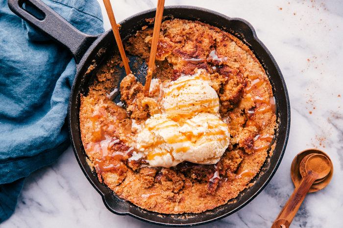 pumpkin cobbler in a skillet with ice cream and caramel sauce on top. 