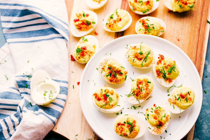 bacon ranch deviled eggs on a white plate garnished with bacon and chive-easy appetizer idea