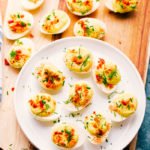 bacon ranch deviled eggs arranged on a white plate for serving.