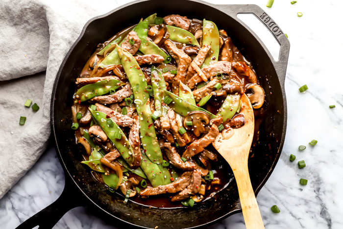 easy beef stir fry by the food cafe made in a skillet for easy preparation and serving set on a white background to enhance the beef and snow peas. 