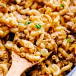 cheeseburger macaroni in a large skillet with a wooden spoon serving pasta.